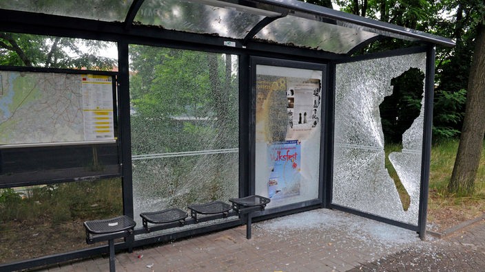 Eine Bushaltestelle mit eingeschlagenem Fenster.