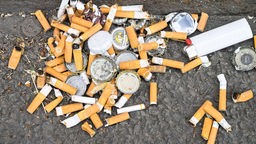 Zigarettenstummel und Müll auf dem Boden.