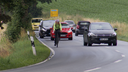 Radfahrer und PKWs auf einer Landstraße