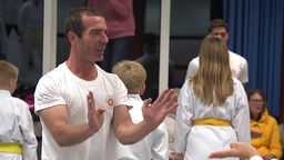 Ein Mann zeigt Kindern Übungen einer Kampfkunst