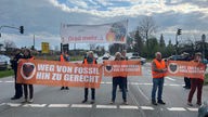 Die Aktivisten blockieren die Straße und halten orangene Banner