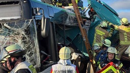 Feuerwehrleute sind dabei, einen Lkw-Fahrer aus dem Führerhaus zu retten