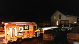 Ein Rettungswagen steht im Dunkeln vor einem Wohnhaus. 