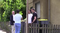 Vier Männer stehen vor einem Haus