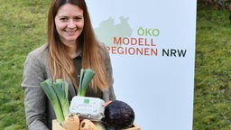 Laura Jäger hält eine Kiste mit Gemüse. 