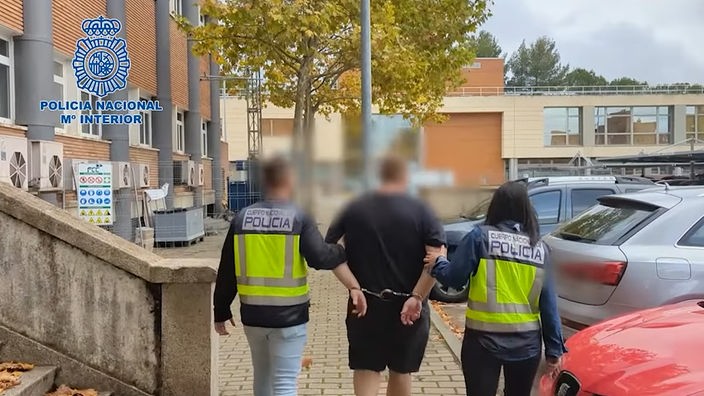 Zwei spanische Polizeibeamte, die den Tatverdächtigen abführen. 