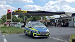 Polizeiauto versperrt Zufahrt auf eine Tankstelle