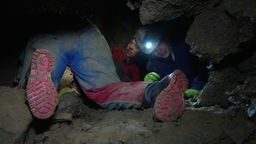Menschen kriechen in einer Höhle in Hemer