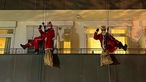 Zwei Menschen in Nikolaus-Kostüm seilen sich an einer Hauswand ab. 