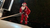 Ein Mann in Nikolaus-Kostüm klettert eine Hauswand hinab.