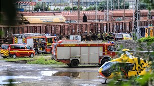 Feuerwehr und Rettungshubschrauber stehen vor den Zügen am Güterbahnhof
