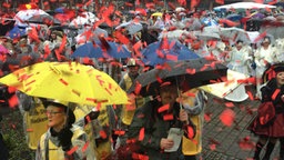 Karnevalisten feiern unter Regenschirmen in Stukenbrock.