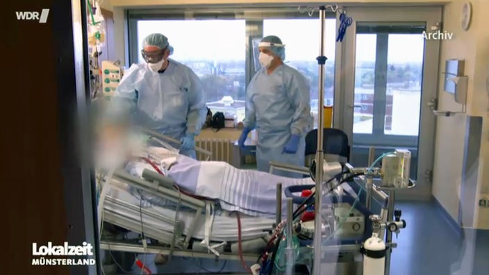 Pfleger stehen am Bett eines Patienten auf der Intensivstation. 