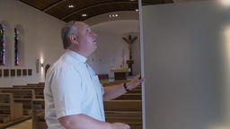 Pfarrer öffnet eine mobile Wand in einer Kirche