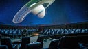 Ein leerer Planetariumssaal mit einem an die Decke projizierten Saturn. 