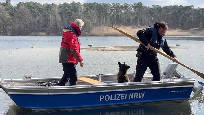 Zu sehen ist ein Polizeiboot mit einem Mann und einem Hund drauf.