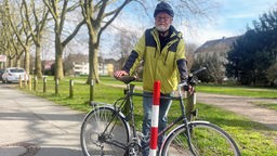 Hans-Ulrich Pohl, Pressesprecher vom ADFC Bielefeld, steht mit einem Fahrrad vor einem Poller. 