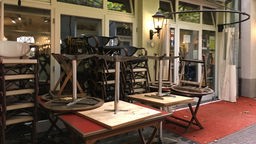 Hochgestellte Tische und Stühle vor einem Restaurant