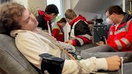Ein junger Mann liegt auf einer Trage, an seinem Arm ein Blutdruckmessgerät