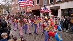 Eine karnevalistische Laufgruppe in US-thematischer Kostümierung läuft über die Rosenstraße in Münster.