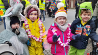 Die Kinder Benno, Santa, Romy und Tom sind als Dino und Wildschwein und mit bunten Mützen und Girlanden auf dem Sassenberger Straßenkarneval.