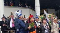 Eine große Gruppe Karnevalisten und Karnevalistinnen mit Komiteemützen in Rheine.