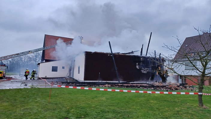 Die ausgebrannte Scheune in Löhne qualmt noch, die Feuerwehr ist mit einer Drehleiter im Einsatz