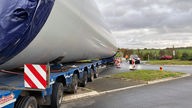 Ein Schwertransporter steht in einem Kreisverkehr. Er hat eine Verkehrsinsel überfahren.