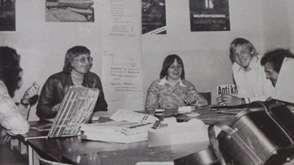Junge Menschen sitzen gemeinsam in den 70ern in einem Raum