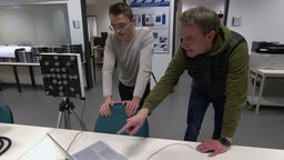 Zwei Experten für Elektrotechnik der Fachhochschule Steinfurt schauen auf einen Laptopbildschirm. 