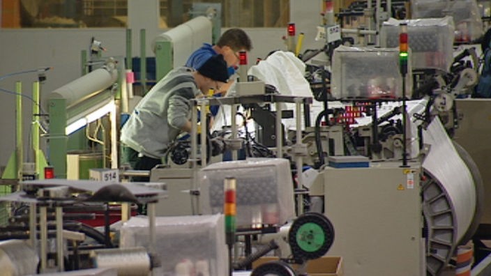 Zwei Arbeiter beugen sich über eine Textilmaschine