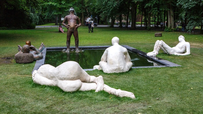 Brunnenskulptur mit mehreren stehenden, sitzenden und liegenden Figuren