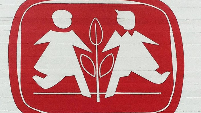Das Logo der SOS-Kinderdörfer zeigt zwei weiße Figuren auf rotem Grund, dazwischen eine Pflanze