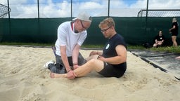Beachvolleyballer Kai von Unified Beach Münster bekommt eine Massage vom Physiotherapeuten