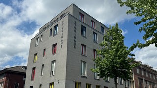 Ein großes graues freistehendes Wohnheim mit horizontaler Aufschrift: Studentenwohnheim