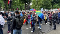 Eine Menschenmenge mit Regenbogenschirmen.