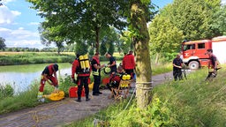 Feuerwehrleute stehen im Einsatz am Ufer des Dortmund-Ems-Kanals.