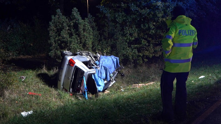 Ein Auto liegt starkbeschädigt in einem Graben. 