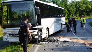 Ein Bus steht nach einem Unfall in einer Kurve. Polizisten nehmen die Schäden auf.