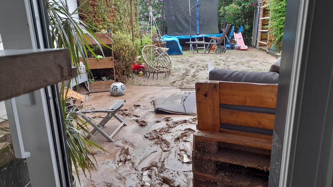 Schlamm von einem Unwetter in Detmold in einem Garten, im Hintergrund ein Trampolin stehend.