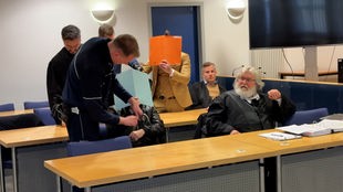 Die beiden zu Haftstrafen verurteilten Drogendealer halten sich eine Mappe vors Gesicht.