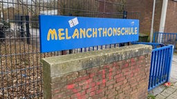 Schild mit der Aufschrift Melanchthonschule vor einem Schultor