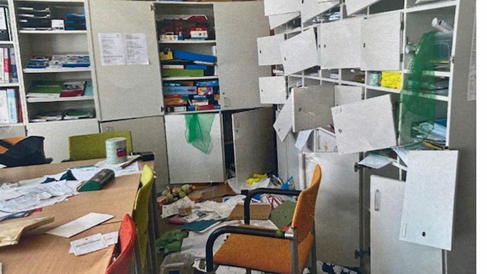 Zerstörte Büroräume mit aufgerissenen Schränken und zerstreuten Sachen