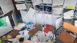 Zerstörte Büroräume mit aufgerissenen Schränken und zerstreuten Sachen auf dem Fußboden