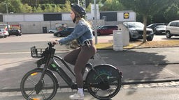  Studentin fährt mit dem E-Bike durch die Stadt 