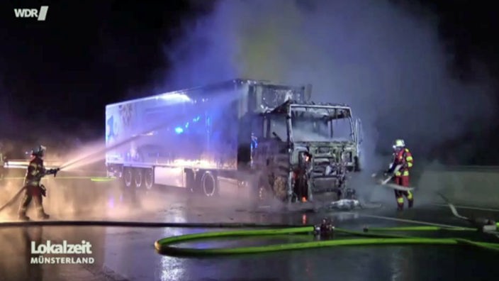 Zwei Feuerwehrleute beim Löschen des ausgebrannten Lastwagens. 