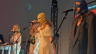 Die Band "Pussy Riot" auf der Bühne an Mikrofonen. 