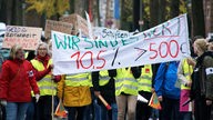 Menschen demonstrieren in gelben Warnwesten mit Transparenten 