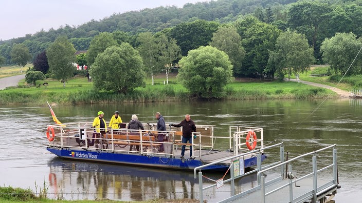 Die Fähre auf der Weser, darauf fünf Personen mit Fahrrädern.