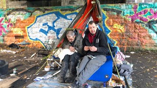 Zwei Obdachlose sitzen in einem Zelt